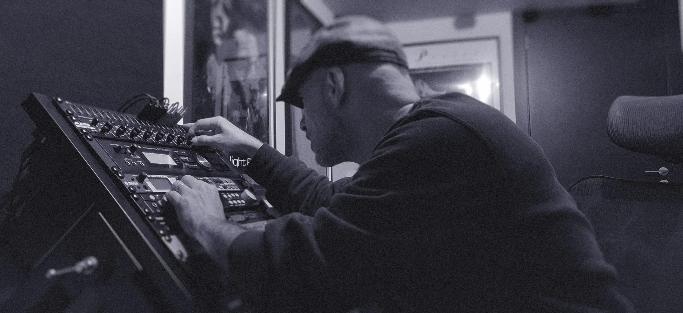 A man adjusts settings on a line mixer and rack modules in a professional recording studio.