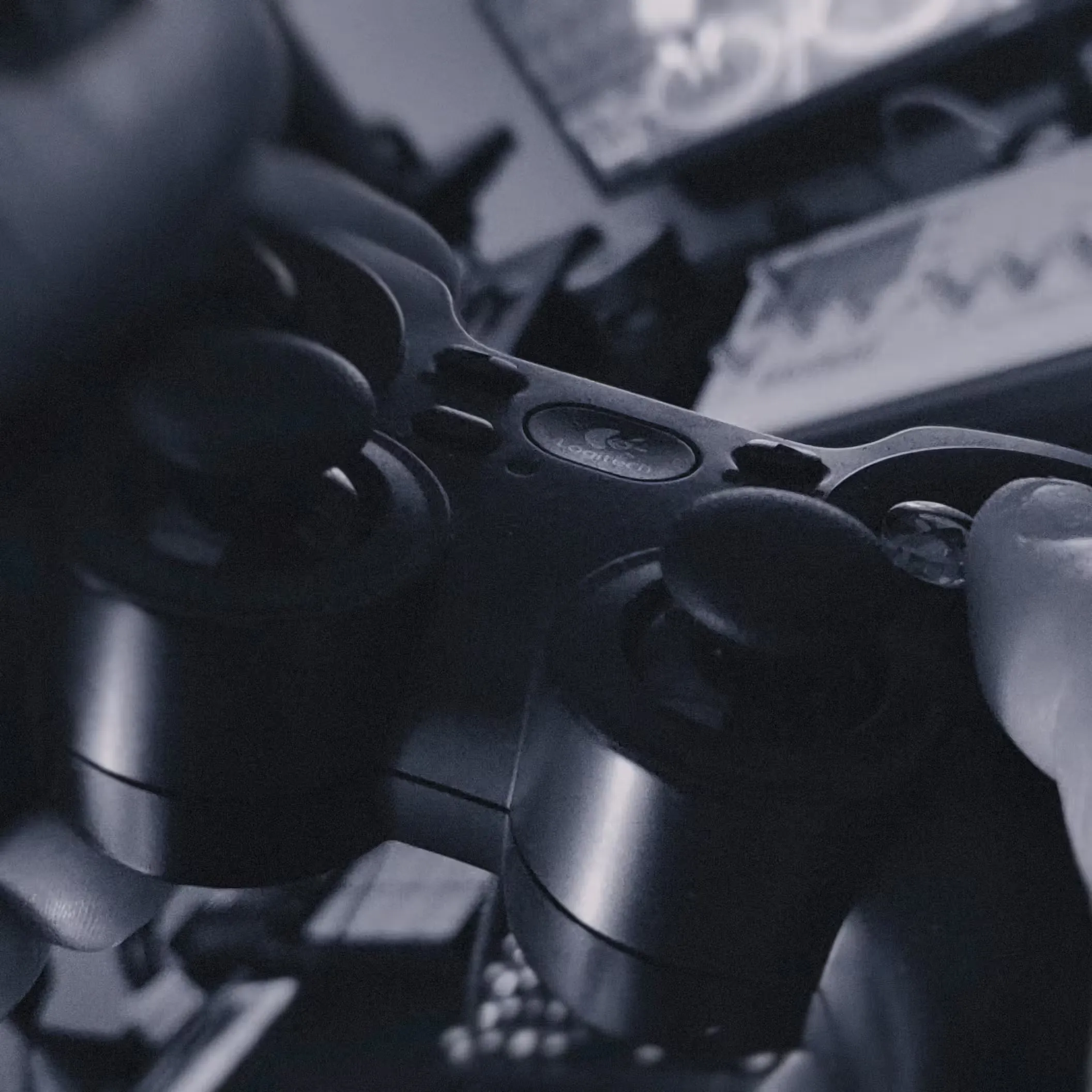 A close-up of hands holding a video game controller in front of a TV screen, with the image in black and white.