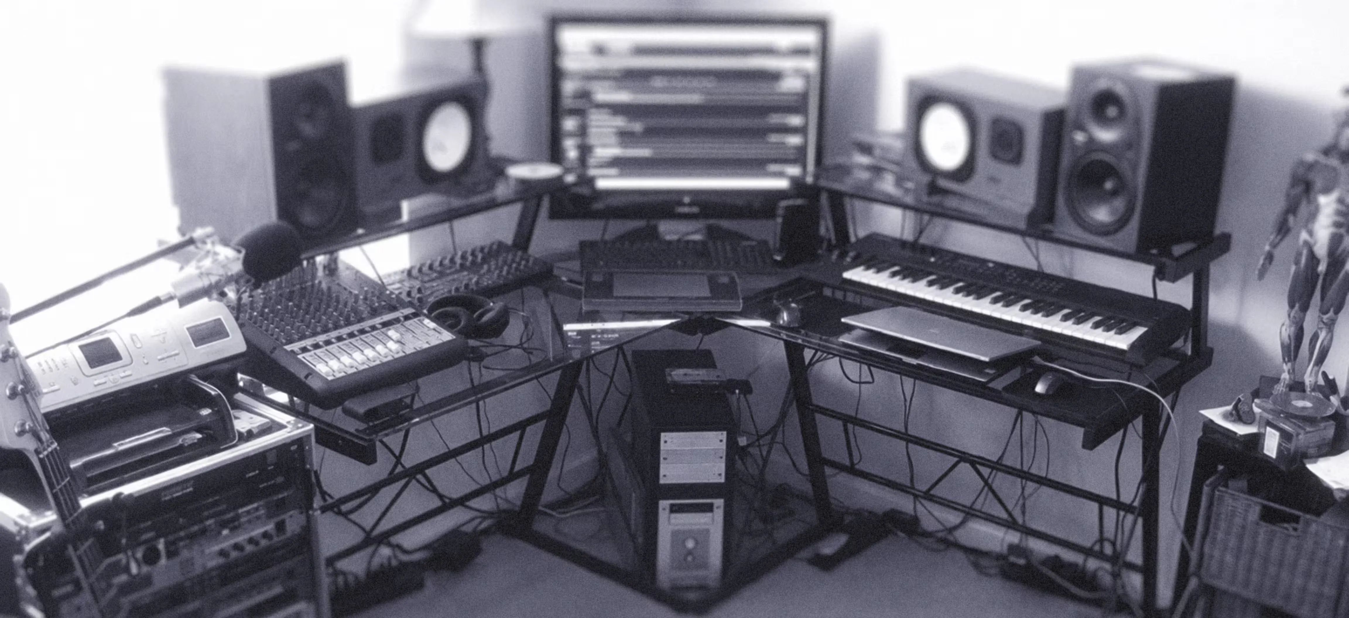 A monochrome image of a music studio showcasing various instruments and audio equipment arranged in the space.