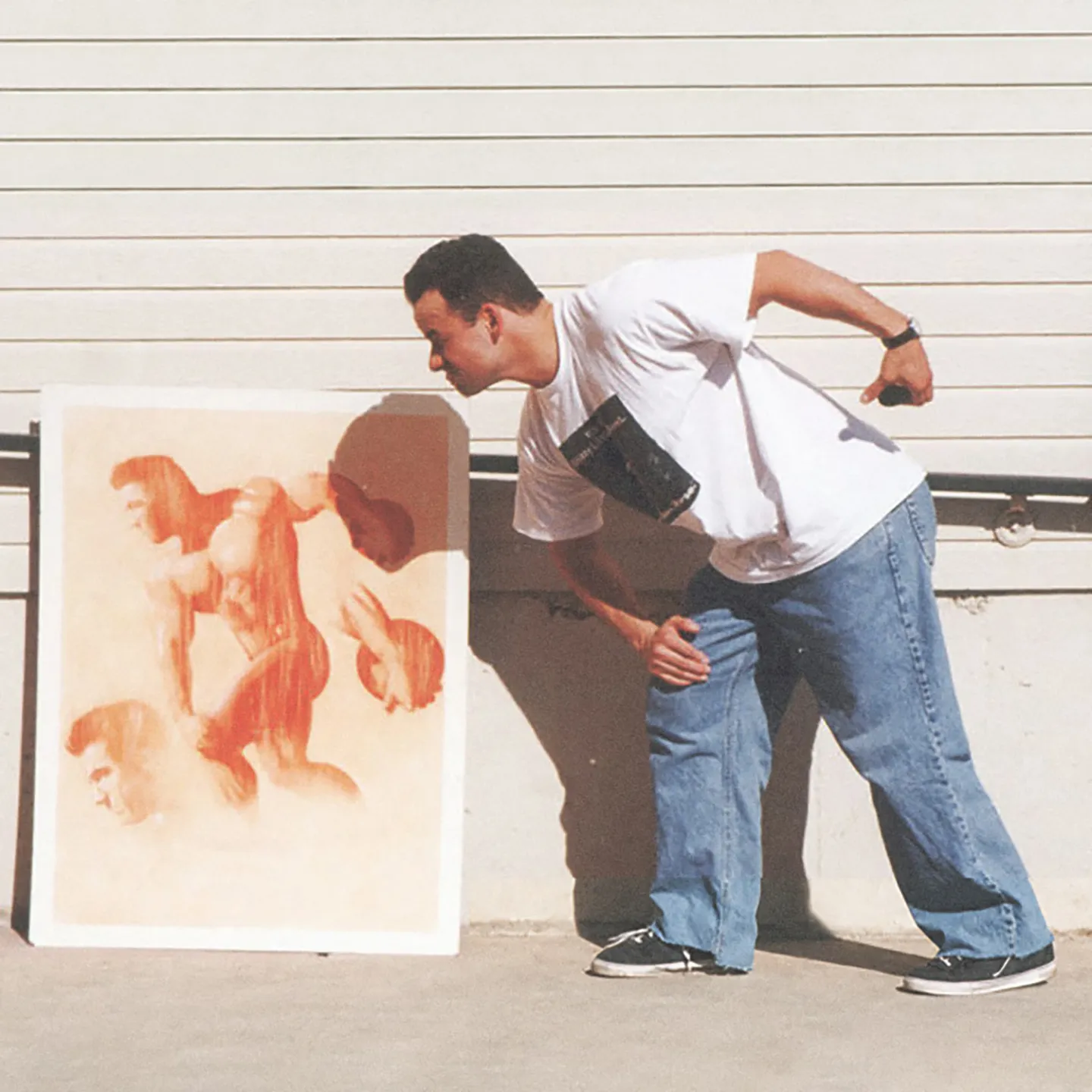 A man leans toward a painting propped against a wall, mimicking the pose of one of the figures depicted in the artwork.