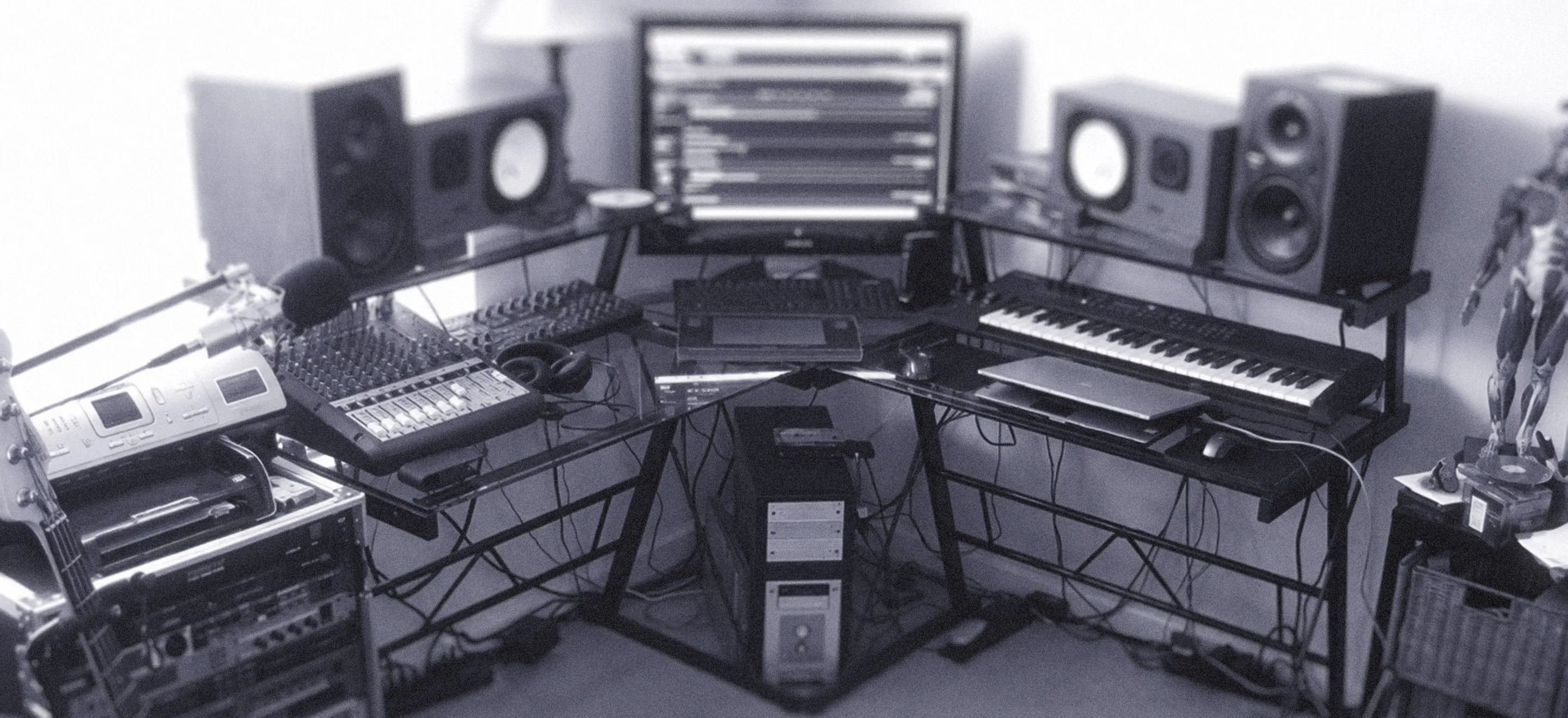 A monochrome image of a music studio showcasing various instruments and audio equipment arranged in the space.